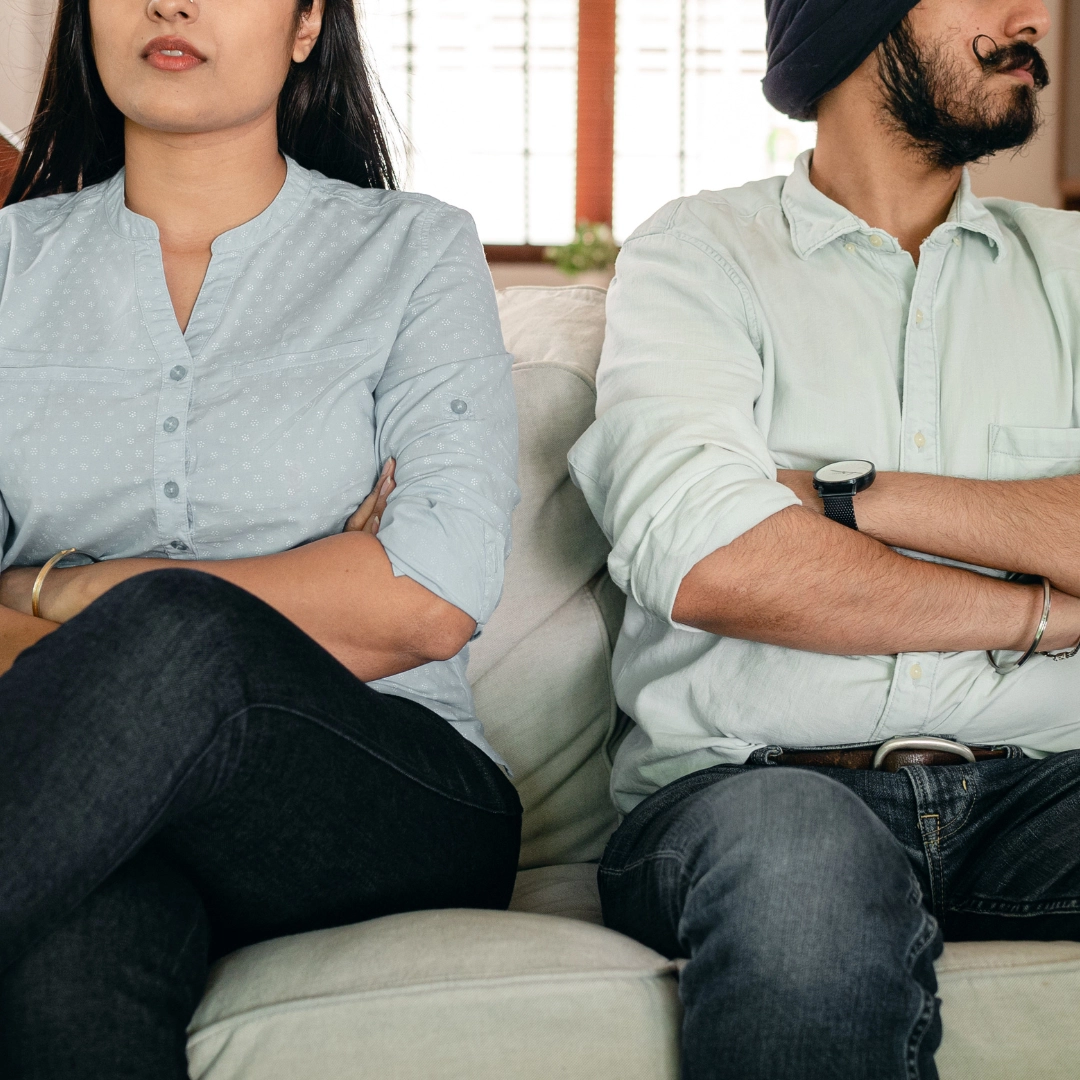 A couple with arms crossed looking away from each other, considering divorce.